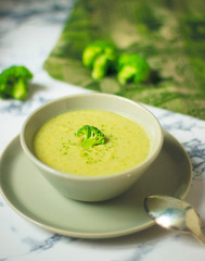 Fresh Broccoli cream soup on two gray ceramic bowl on plate with spoon on marble background,vegetarian food,healthy concept