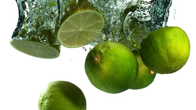 Super slow motion of falling lime pieces into splashing water isolated on white background. Filmed on high speed cinema camera, 1000 fps.