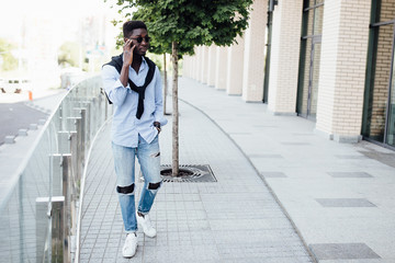 Full length portrait of a happy young man, tourist walking and holding on sunglasses.