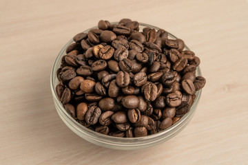 coffee beans in a glass bowl on wooden background