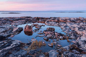 Canada, Nunavut, Territory, Setting midnight sun lights clouds above rocky coastline of Harbour Islands along Hudson Bay near Arctic Circle