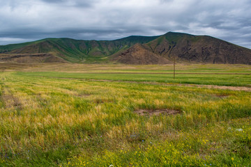 Fototapeta premium Turkey, aerial view of the breathtaking landscape on the dirt and winding road on the plateau around Mount Ararat, Agri Dagi, with rocky peaks, hills, grassland and flowers near the Ishak Pasha Palace