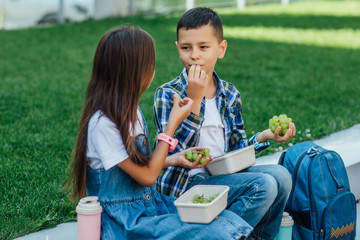 Two kids, with at smart watches on hands. After school with grape. Lunch time.