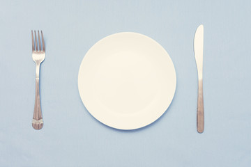 Cutlery set with plate. Dish, fork and knife, blue background, closeup, top view