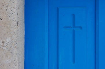 Greece, Santorini, Thira, Oia. Christian cross symbol engraved in blue door.