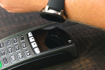 Customer making wireless or contactless payment using smartwatch. Store worker accepting payment with nfc technology