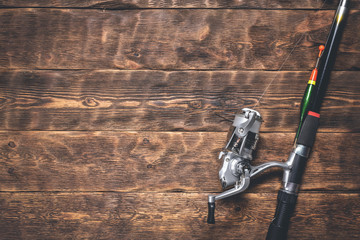Fishing rod on a wooden table. Fishing flat lay background with a copy space.