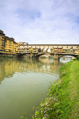 Fototapeta na wymiar Italy, Florence. Historic Ponte Vecchio bridge is seen from the banks of the River Arno. 