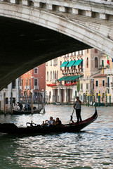 Obraz na płótnie Canvas Italy, Venice. Tourists take pictures from a gondola as they cross under the Rialto Bridge.