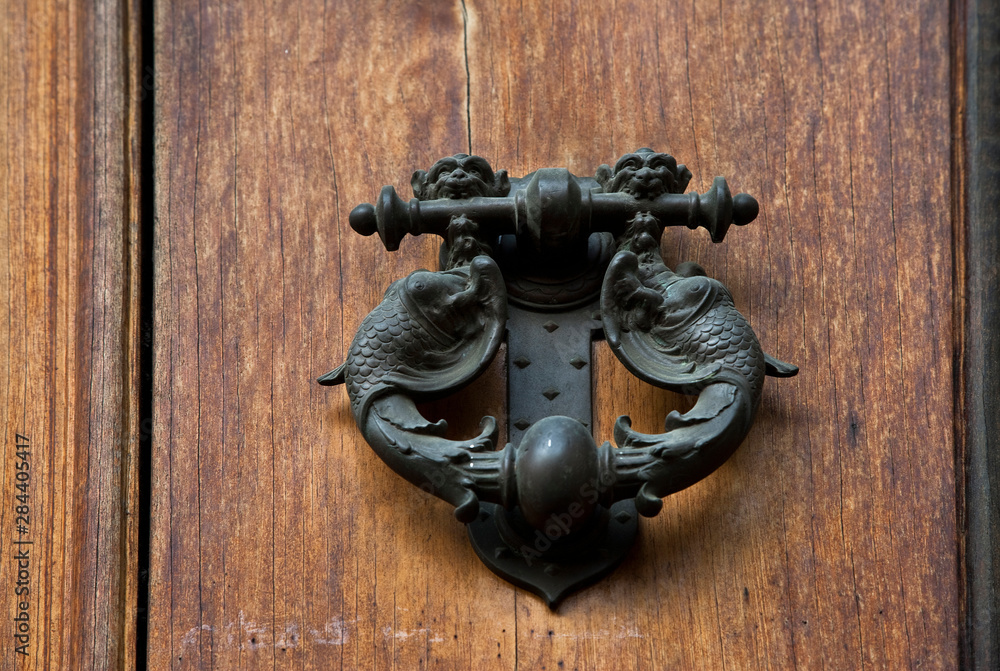 Sticker sienna, tuscany, italy - closeup of ornate, metal door knocker on a wooden door.