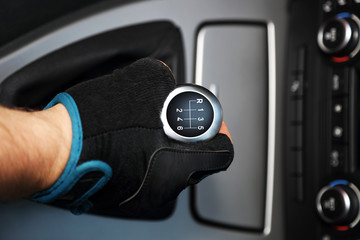 Dłoń w rękawiczce na sześcio biegowej dźwigni zmiany biegów w samochodzie osobowym. - obrazy, fototapety, plakaty