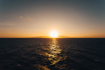 Sun about to set behind the horizon on the sea