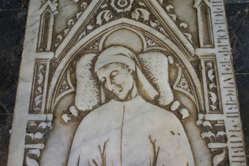 Italy, Tuscany, Pisa, Piazza dei Miracoli. Marble sepulcher cover inside the Battistero. Elegant tunic and slippers.