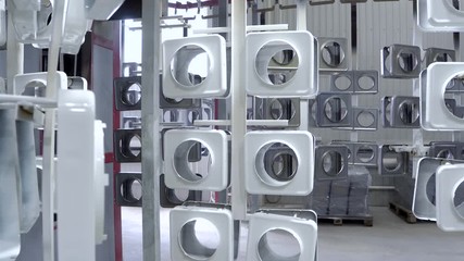 line for painting metal products in white color coating. Square metal products with a round hole hang on mounts after powder painting