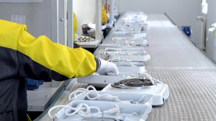 manufacture of electrical products. Hands in white gloves put on the conveyor belt finished products. Manufacture of electric tiles and heaters. Close up