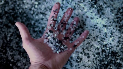 Plastic black and white granules are poured from the hand. Plastic granules, dye, polymer granules are used for the production of plastic products