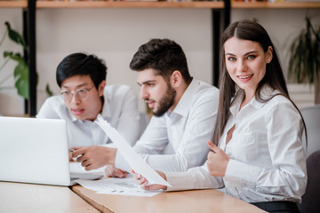woman working in the office shows thumbs up with diverse male co-workers
