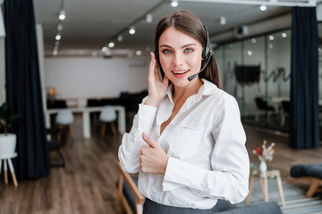 Fototapeta premium female tech support agent with headset answering business calls in company office