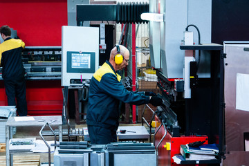 Worker operator bending metal sheet process by sheet bending machine for bus manufactuing part,...