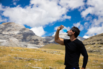hombre deportista bebiendo bebida energetica despues de hacer deporte en la montaña