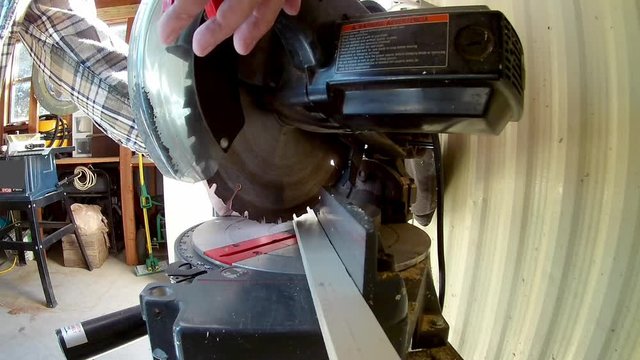 Person cuts through thin wood with an electric mitre saw
