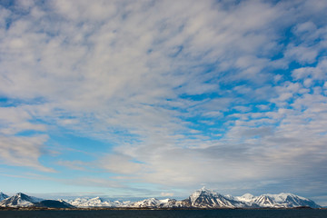 Norway. Svalbard. Spitsbergen. Forlandsundet. Snowy mountains and cirrus clouds under the midnight...