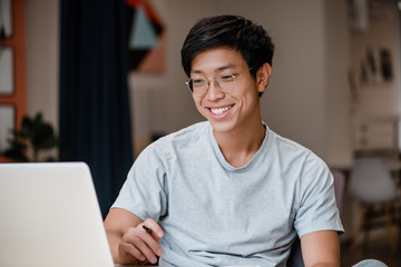 Obraz premium smiling asian man working on laptop