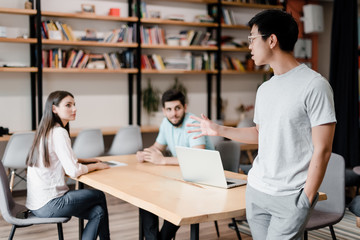 asian man talks to employees in the office