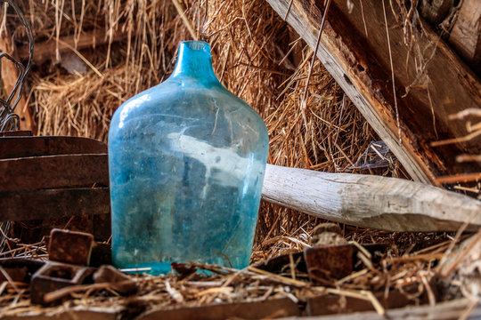 Romania. Turquoise glass bottle in hay barn.
