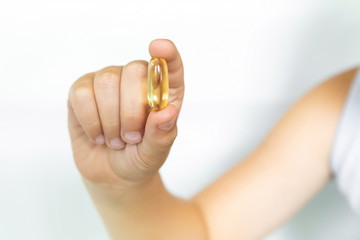 Children's hands hold the omega 3 capsule isolated on white background. The concept of health care and longevity.