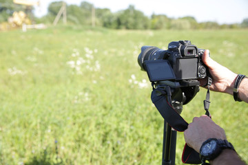 Close-up. Digital camera in hand photographer or videographer with monopod.