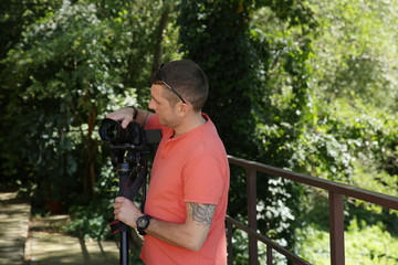 photographer or videographer with a digital camera in his hand and with a monopod. Outdoors....