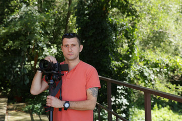 photographer or videographer with a digital camera in his hand and with a monopod. Outdoors. Equipment.