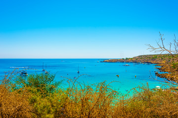  blue sea with clear water, mountains, yachts and the beach on the panorama of Konnos Bay Cyprus