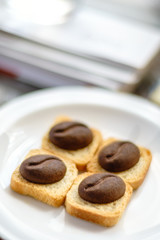 Obraz na płótnie Canvas Four brown cookies with shape of cocoa beans lay on square breadcrumbs in white plate.
