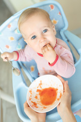 Adorable cute caucasian blond toddler boy eating tasty vegetable soup in chair at kithcen indoor....