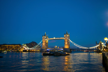Obraz premium Tower Bridge on the Thames, brightly light at night, is a popular tourist attraction in London.