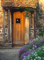 Fototapeta na wymiar England, Chippenham. An old wooden door welcomes visitors to a thatched-roofed cottage in Chippenham, Wiltshire, England.