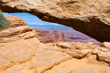 Arches National Park looking through  an arch at mountains with a bright blue sky and wispy white clouds © Joni