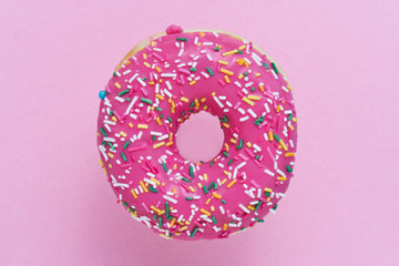 Sprinkled Pink Donut. Glazed sprinkled donut on pink background. Top view, copy space