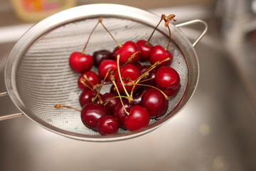 Obraz na płótnie Canvas red juicy tasty cherry in a colander