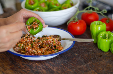 Woman is filling  green pepper.