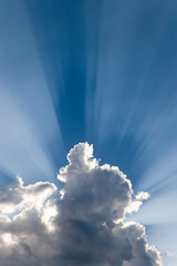 Crepuscular or God's rays streak past cloud. 