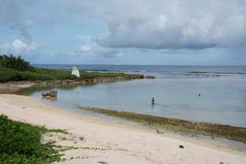 Micronesia, Mariana Islands, US Territory of Guam, Talofofo. Southern Guam, young boy on beach in shallow cove.