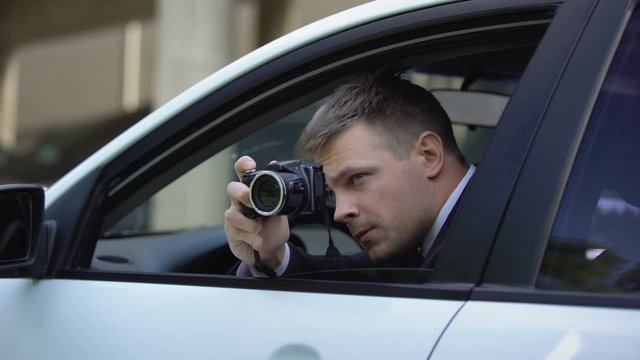 Man with camera opening car window and making photo, private detective spying