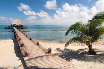 Placencia, Belize. Roberts Grove Resort, Pier leads from sand beach to thatch roof dock used as entertainment bar at night.