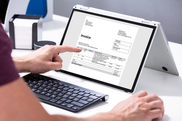 Businessman's Hands Working On Invoice On Laptop