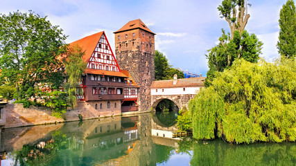 Nuremberg, Germany, beautiful old bridge with medieval tower and half timbered house along the river with reflections - obrazy, fototapety, plakaty