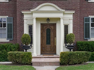 elegant wooden front door with portico and shrubbery