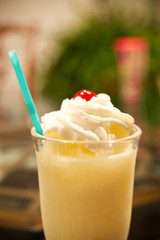 A cold pina colada with whipped cream and a cherry on top.